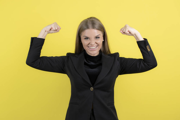Portrait of young businesswoman showing her fist on yellow background. High quality photo - Fotó, kép