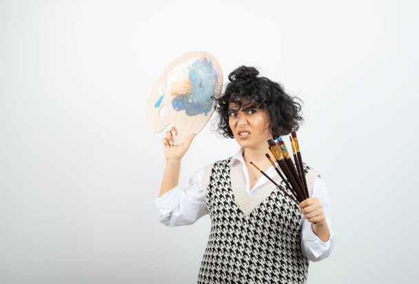 A young woman artist standing with brushes and holding palette paint . High quality photo - Photo, Image