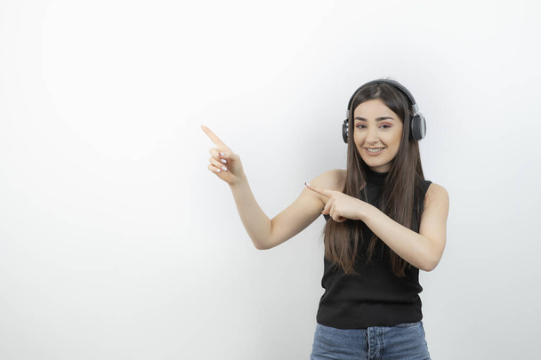 Muotokuva nuoresta naisesta kuulokkeissa kuuntelemassa laulua valkoisella. Laadukas kuva - Valokuva, kuva