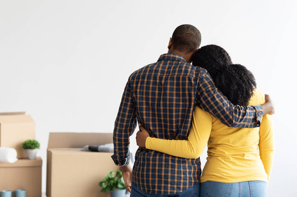 Black Couple Standing In Room With Cardboard Boxes After Moving, Rear View - Foto, Imagem