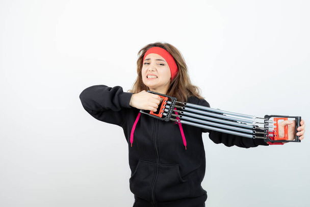 Morena deportista sosteniendo mancuernas de colores sobre la pared blanca - Foto, Imagen