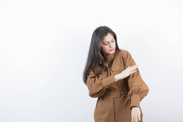 Immagine di una modella bruna in piedi e posa contro il muro bianco. Foto di alta qualità - Foto, immagini
