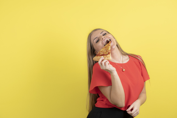 Зображення привабливої жінки, що їсть шматочок смачної піци. Високоякісна фотографія
 - Фото, зображення