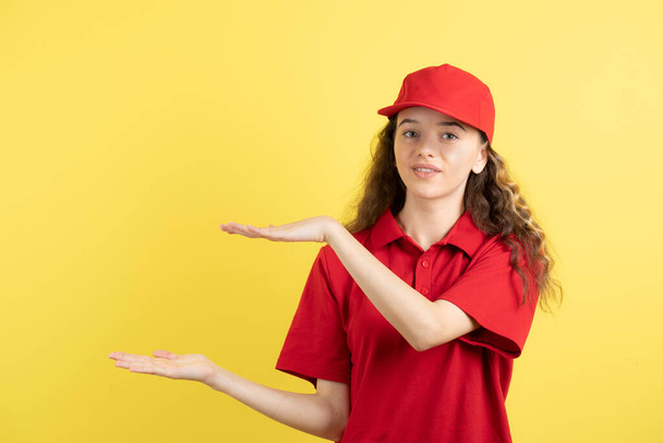 Giovane donna adolescente corriere in uniforme rossa che tiene aperto lo spazio. Foto di alta qualità - Foto, immagini