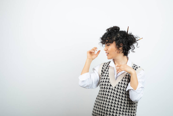 Femme artiste debout et posant avec un pinceau dans son chignon de cheveux. Photo de haute qualité - Photo, image