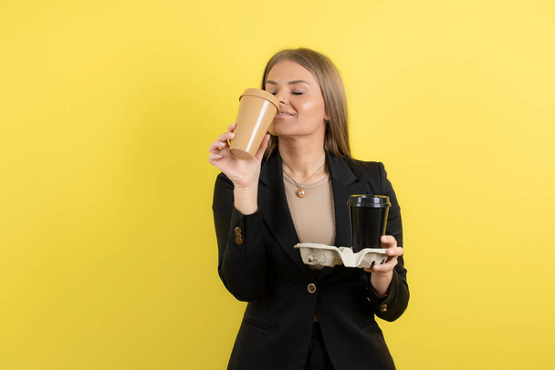 Photo of positive young woman smells aroma of coffee on yellow background. High quality photo - Fotoğraf, Görsel