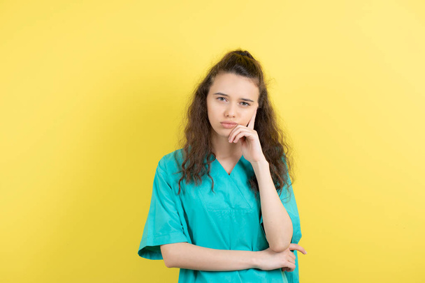 Image of teen female nurse standing on yellow background. High quality photo - Photo, Image