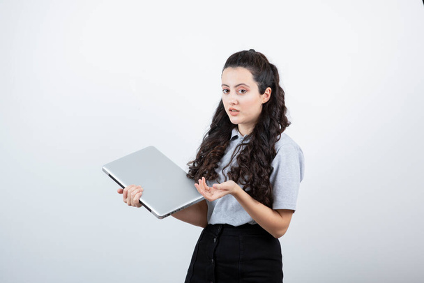 Portrait of a young brunette girl holding laptop computer over white background. High quality photo - Foto, Imagem