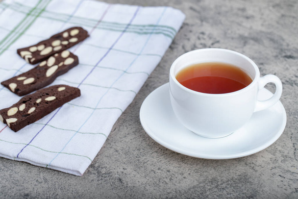 Crunchy cocoa biscuits with nuts and cup of tea on stone background. High quality photo - Foto, Imagem