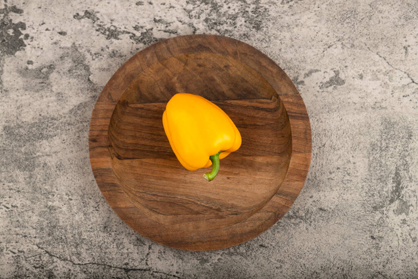 Yellow sweet bell pepper placed on wooden plate. High quality photo - Fotó, kép