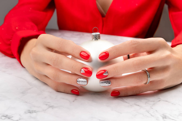 Beautiful groomed womans hands with hristmas nail design on marble background - Фото, изображение