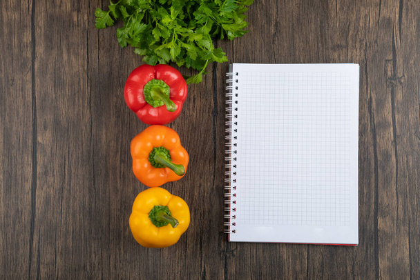 Colorful bell peppers, parsley and notebook on wooden background. High quality photo - Foto, Imagen
