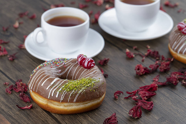 One chocolate doughnut with cups of black tea placed on a wooden table . High quality photo - Photo, Image