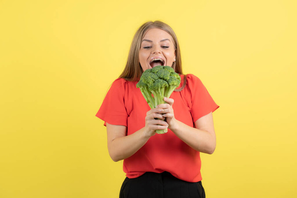 Egy gyönyörű nő képe, aki nagy zöld brokkolit eszik. Kiváló minőségű fénykép - Fotó, kép