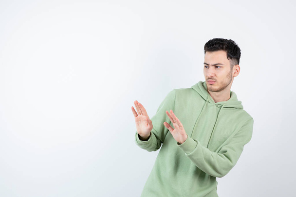 Portrait of male handsome man in hoodie staying away from something. High quality photo - Photo, Image