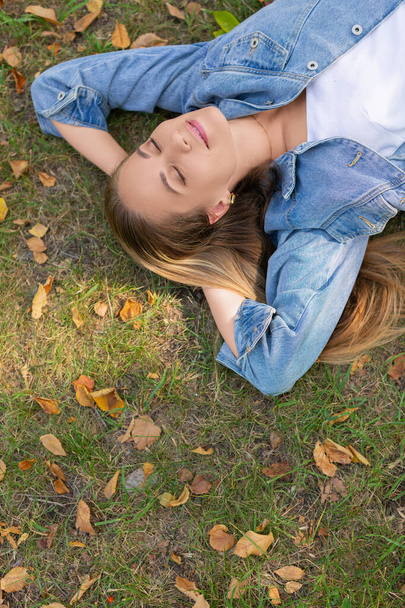 Концепція цифрового детоксикатора - стомлена молода жінка лежить у парку на траві із закритими очима
. - Фото, зображення