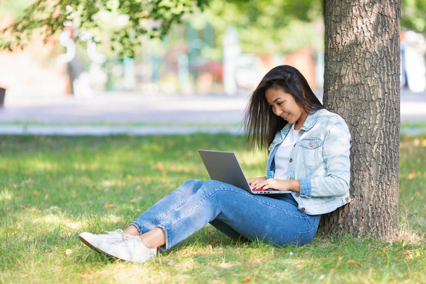 Portrét asijské ženy s laptopem v městském parku během on-line pracovní nebo vzdálené on-line vzdělávání. - Fotografie, Obrázek