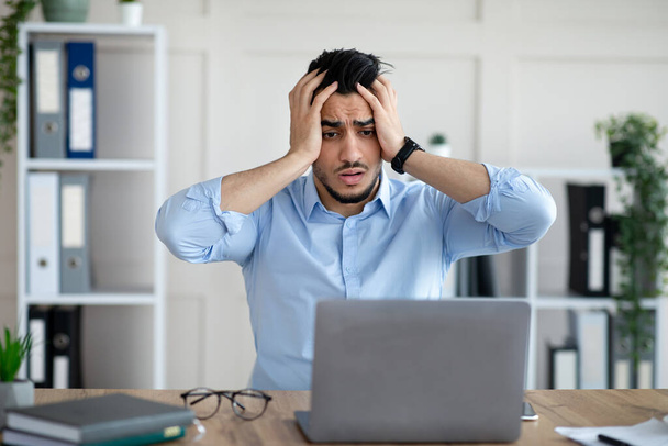 Homme d'affaires arabe désespéré ayant trop de travail, faisant des erreurs, ne peut pas respecter la date limite, souffrant de maux de tête au travail - Photo, image