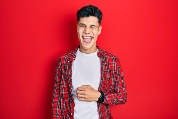 Jeune homme hispanique portant des vêtements décontractés clin d'oeil en regardant la caméra avec une expression sexy, gai et heureux visage.  - Photo, image