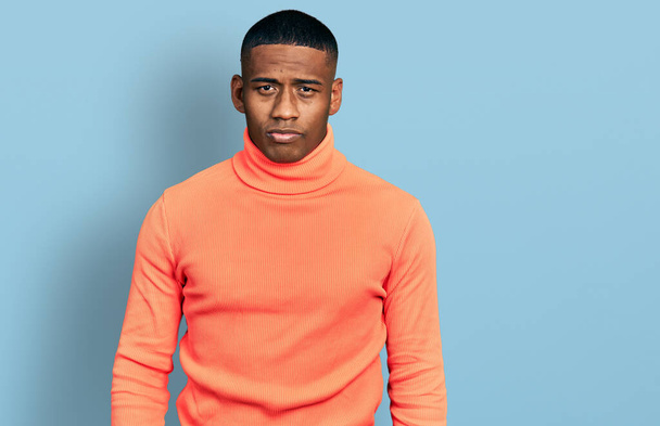 Nuori musta mies yllään oranssi poolopaita pusero vakava ilme kasvoilla. yksinkertainen ja luonnollinen kameraan katsominen.  - Valokuva, kuva