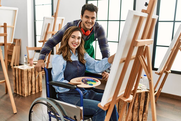 Profesor y estudiante de pintura discapacitado sentado en silla de ruedas sonriendo pintura feliz en la escuela de arte. - Foto, Imagen