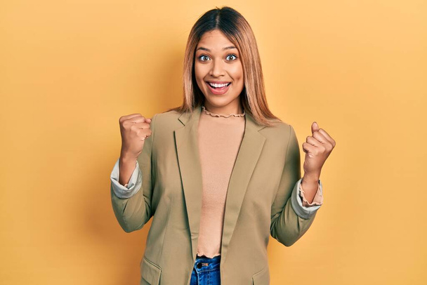 Beautiful hispanic woman wearing business jacket celebrating surprised and amazed for success with arms raised and open eyes. winner concept.  - Zdjęcie, obraz