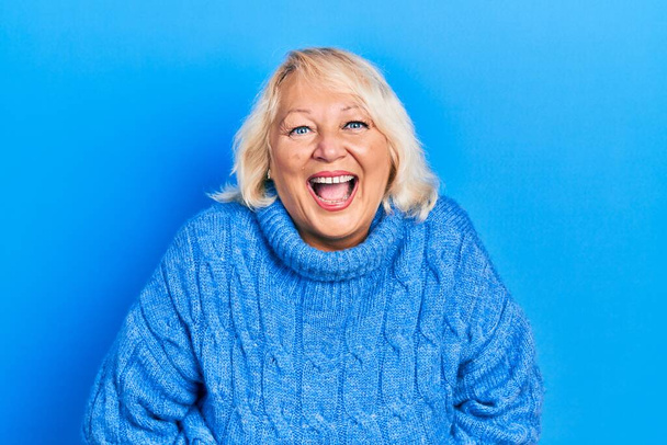 Middelbare leeftijd blonde vrouw dragen casual kleding glimlachen en hard lachen hardop omdat grappige gekke grap met handen op het lichaam.  - Foto, afbeelding