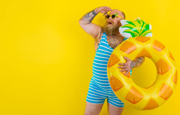 Товстий здивований чоловік з перукою в голові готовий плавати з пончиком рятівник
 - Фото, зображення