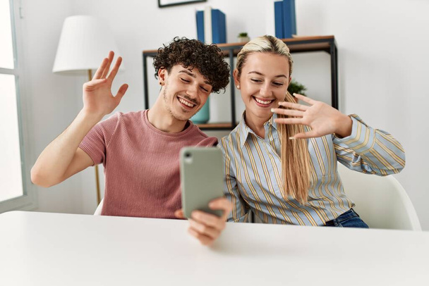 Fiatal pár mosolyog boldog, hogy videohívást használ okostelefon otthon. - Fotó, kép