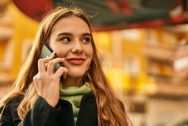 Young blonde girl smiling happy talking on the smartphone at the city. - Foto, afbeelding