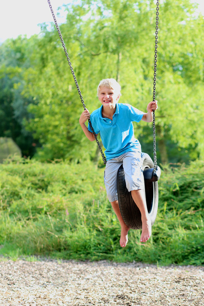 Happy boy swinging in the park - Photo, image