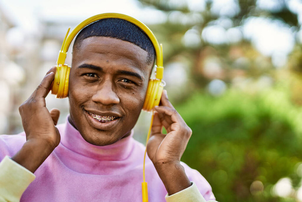 Young african american man smiling happy using headphones at the city. - Foto, immagini