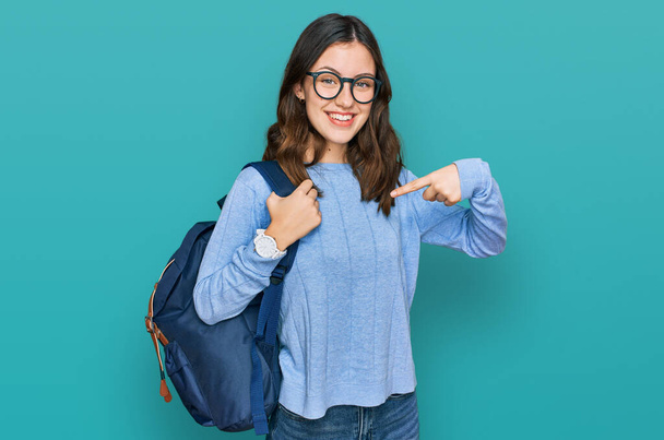 Menina bonita nova usando mochila estudante apontando dedo para um auto sorrindo feliz e orgulhoso  - Foto, Imagem