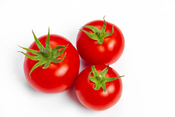 Tři červená čerstvá rajčata na světlém pozadí. Pohled shora. Koncept vegetariánských potravin. - Fotografie, Obrázek