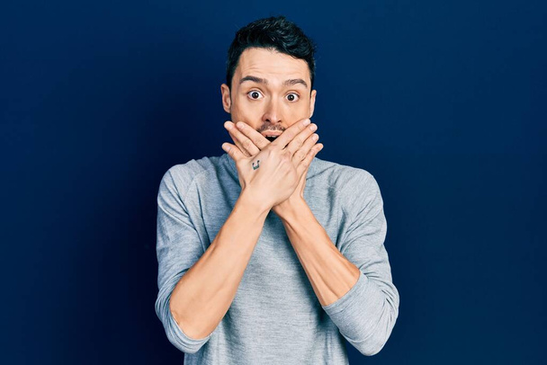 Young hispanic man wearing casual clothes shocked covering mouth with hands for mistake. secret concept.  - Fotoğraf, Görsel