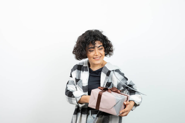 Winsome female model in checkered t-shirt holding present with brown bow. High quality photo - Fotoğraf, Görsel