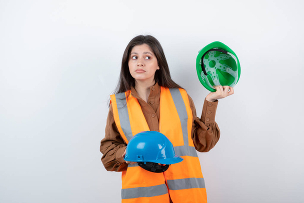 Фотографія жінки-інженера в жилеті, що позує з шоломами. Високоякісна фотографія
 - Фото, зображення