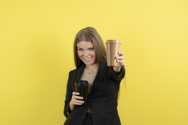Fotografie pozitivní mladé ženy držící šálky kávy na žlutém pozadí. Kvalitní fotografie - Fotografie, Obrázek