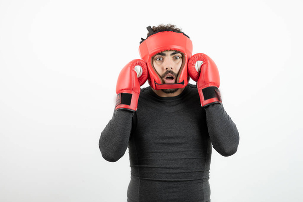 Retrato de un joven con casco de boxeo y guantes sobre una pared blanca. Foto de alta calidad - Foto, imagen