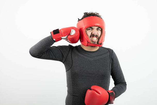 Portrait of young man with boxing helmet and gloves over white wall . High quality photo - Foto, Imagen