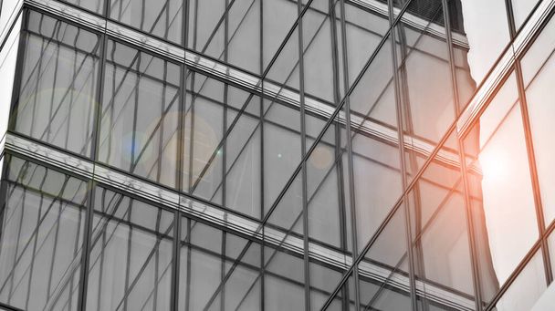 Modern architectural details. Modern glass facade with a geometric pattern. Contemporary corporate business architecture. Red sun on horizon. Black and white toned image. - Photo, Image