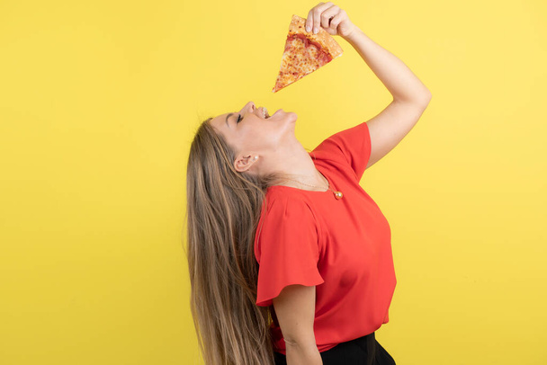 Lezzetli bir dilim pizza yiyen çekici bir kadın görüntüsü. Yüksek kalite fotoğraf - Fotoğraf, Görsel