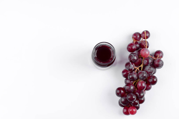 Banda winogron ze szklanym dzbankiem soku umieszczonym na białym stole. Wysokiej jakości zdjęcie - Zdjęcie, obraz