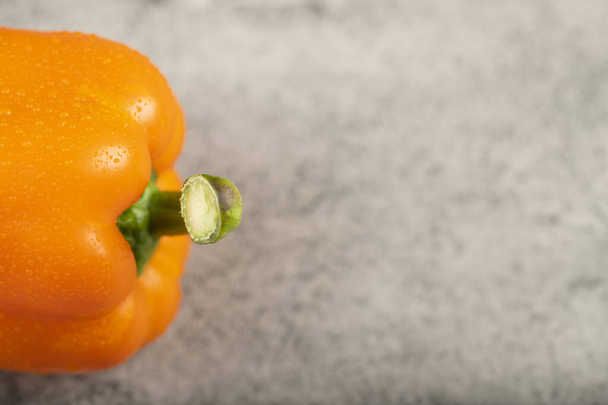 Orange fresh bell pepper with water drops on stone background. High quality photo - Fotografie, Obrázek