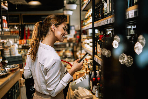 Beautiful young and elegant woman buying some healthy food and drink in modern supermarket or grocery store. Lifestyle and consumerism concept. - Photo, Image