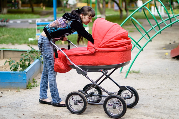 Young mother looks in a baby carriage  - Photo, Image