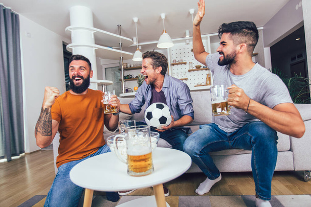 Felizes amigos masculinos ou fãs de futebol assistindo futebol na TV e celebrando a vitória em casa. - Foto, Imagem
