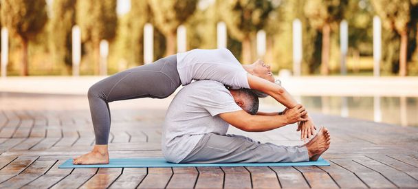 Fit älteres Familienpaar beim Partner-Yoga an frischer Luft draußen am sonnigen Morgen, älterer Mann trägt Frau auf dem Rücken beim gemeinsamen Training auf Fitnessmatte im Stadtpark - Foto, Bild