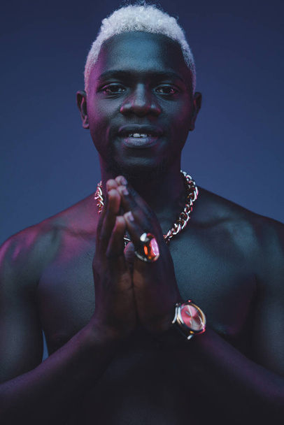 Αφρικανός κρατάει τα χέρια του ενωμένα σε σκοτεινό φόντο. - Φωτογραφία, εικόνα