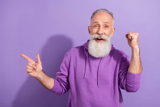 Retrato de anciano jubilado jubilado de moda hombre de pelo gris que muestra el espacio de copia que se divierte aislado sobre el color violeta púrpura fondo - Foto, imagen